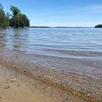 Clear shallow lake water at a sandy shoreline with light ripples catching the sun